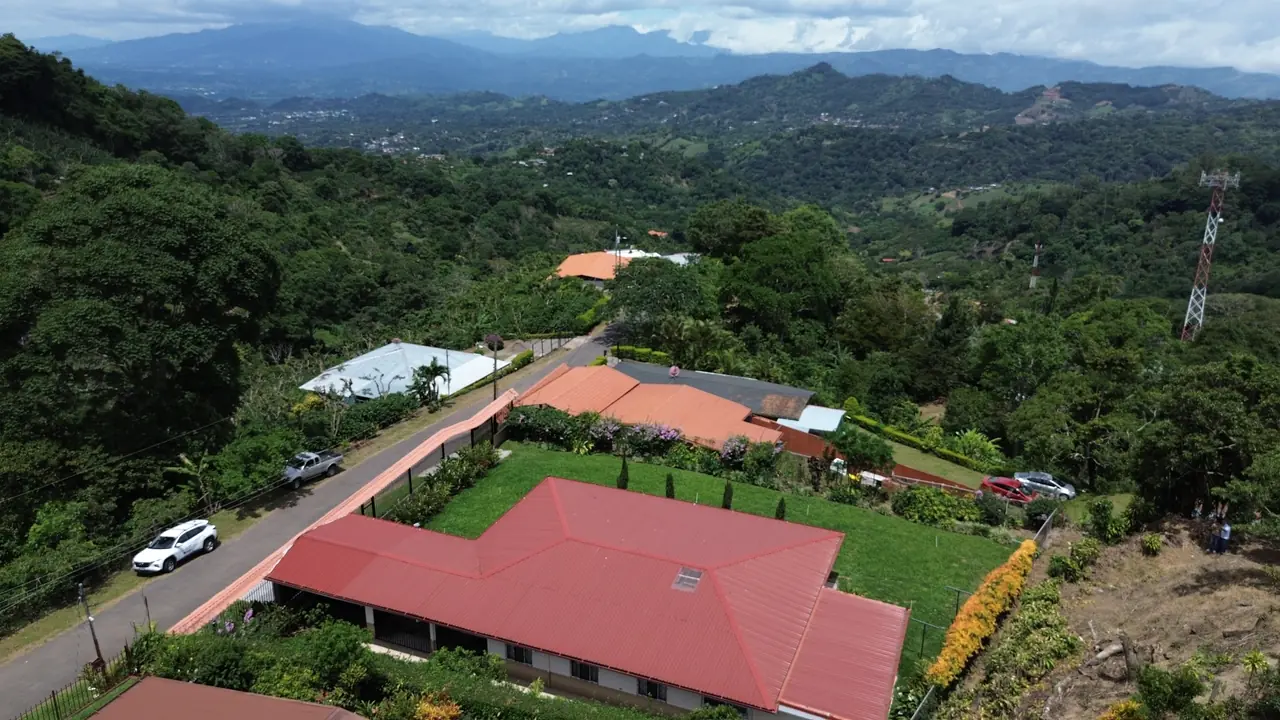 Casa con techo rojo rodeada de jardín y vista a las montañas en Naranjo, Alajuela